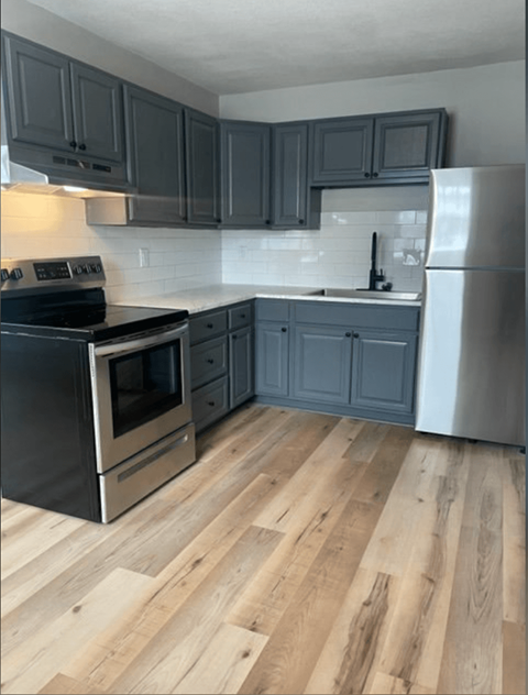 a kitchen with gray cabinets and stainless steel appliances